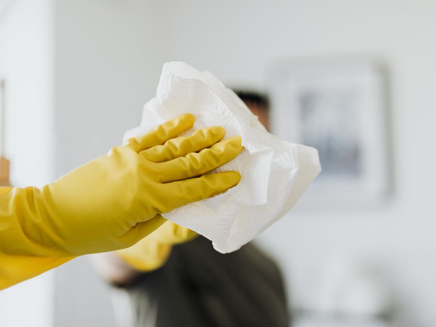 A cleaner in gloves wiping a surface spotless