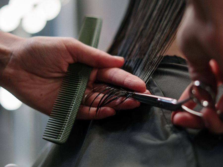 Stylist trimming a client's hair with scissors and comb